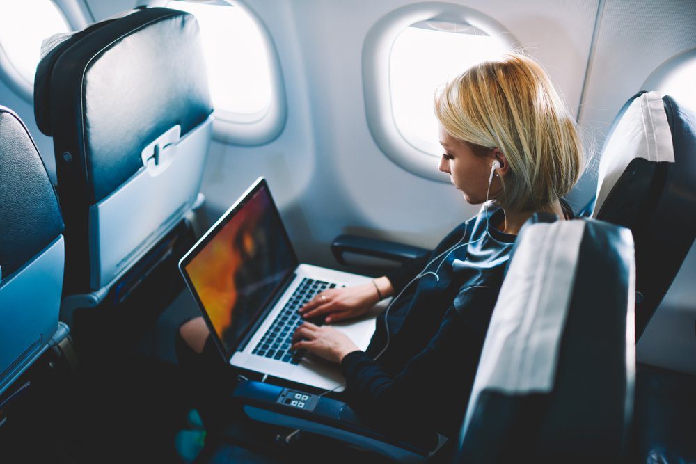 Woman-sitting-on-a-plane-using-a-laptop