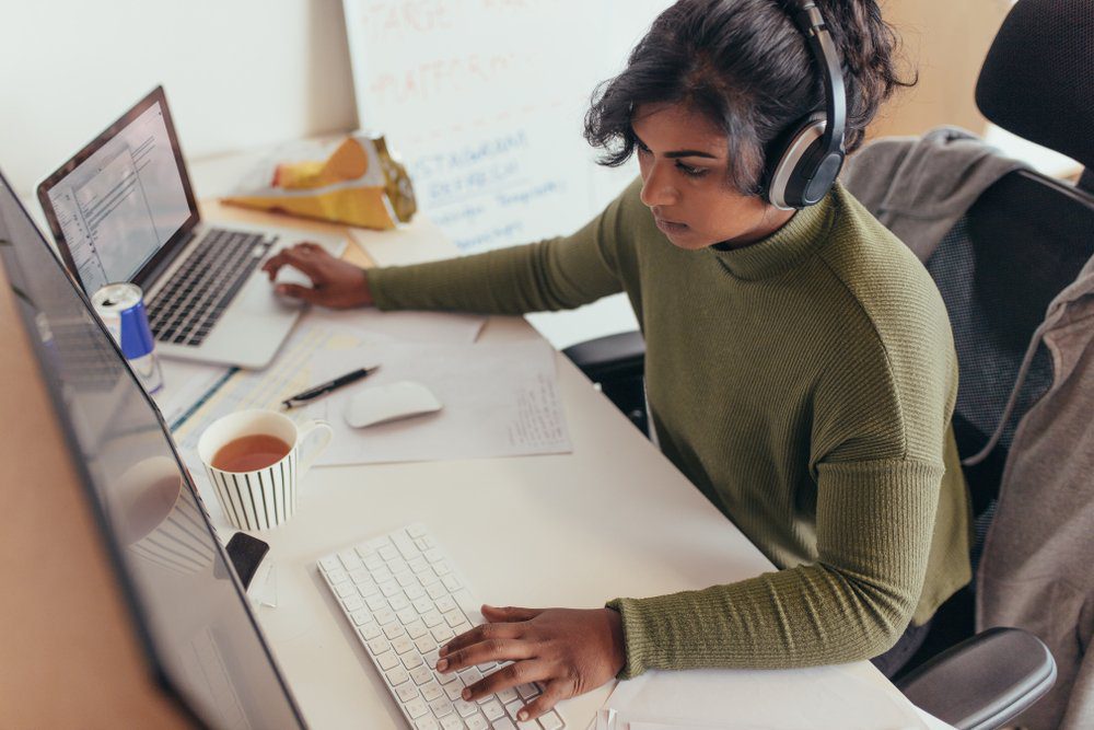 woman with headphones on working remotely in her homes